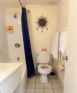 a bathroom with a toilet and a blue shower curtain at Hawaiian Monarch 2508 condo in Honolulu