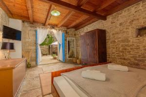 a bedroom with a bed and a stone wall at Guest House Eleonora in Čabrunići
