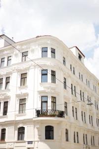 a white building with a balcony in front of it at HeyMi Apartments Zentagasse in Vienna