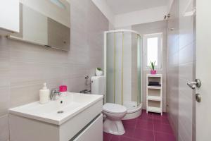 a white bathroom with a toilet and a sink at The Whitehouse Apartment in Brodarica