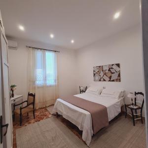 a white bedroom with a large bed and a table at A un Passo dal Tramonto in Marsala