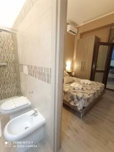 a bathroom with a sink and a toilet and a bed at Villa Alfea CAMERE in Porto Cesareo