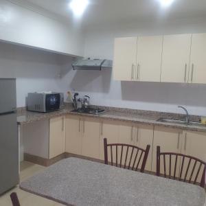 une cuisine avec des armoires blanches, une table et un micro-ondes dans l'établissement RESIDENCE OUARZAZATE, à Ouarzazate