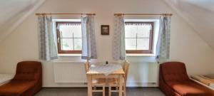 um quarto com duas cadeiras e uma mesa e duas janelas em Pension Helena Honesová em Horská Kvilda