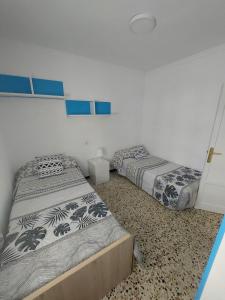 2 Betten in einem weißen Zimmer mit blauen Akzenten in der Unterkunft piso villavarela in Tarifa