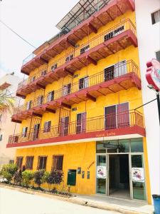 Bungalows El Rincon de La Riviera في رينكون دي غوايابيتوس: مبنى اصفر ويوجد بلكونات بجانبه