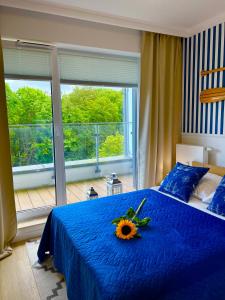 a bedroom with a blue bed with a sunflower on it at Apartament Nadmorski Hampton in Kołobrzeg +16 photos