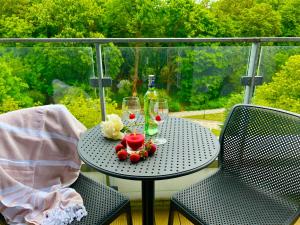 a table on a balcony with a bottle and glasses at Apartament Nadmorski Hampton in Kołobrzeg