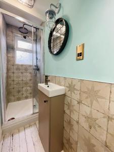 a bathroom with a sink and a shower and a mirror at The Rambler's Rest Cottage, Parkgate, Wirral in Parkgate