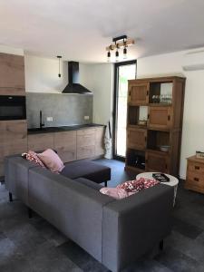 uma sala de estar com um sofá cinzento e uma cozinha em Vakantiewoning De Kleine Duinberg - Chalet Nr 9 em Retie