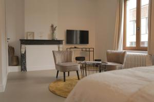 a bedroom with a fireplace and two chairs and a tv at MAISON KITOKO in Ghent