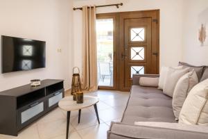 a living room with a couch and a tv and a table at IFESTOS APARTMENTS in Ierissos