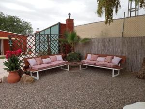 eine Terrasse mit 2 Bänken und rosa Kissen in der Unterkunft Home Benitez Pizarra in Pizarra