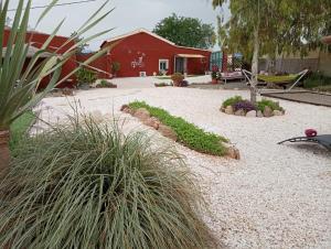 um jardim com cascalho e plantas em frente a um edifício vermelho em Home Benitez Pizarra em Pizarra