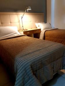 1 dormitorio con 2 camas y escritorio con lámpara en eSuites Dalmacio Vélez 571 en La Rioja