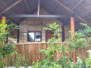 a wooden cabin with a fence and a window at Big BamBoo Beach Resort Sipalay in Sipalay