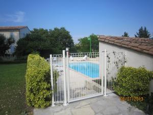 a white gate with a swimming pool behind it at La Frandomière in Saint-Martin-de-Londres