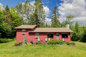 a red house on a green field with trees at Notch Lodge in Franconia