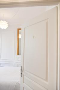een witte slaapkamer met een deur naar een bed bij Les Matelots Rouen Centre by MyFrenchPAT in Rouen