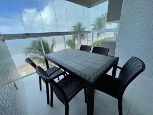 d'une table et de chaises sur un balcon avec vue sur la plage. dans l'établissement Branco Haus - Pé na areia do Bessa, à João Pessoa