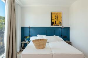 a bed with a blue headboard in a room with a window at Som Nit Port Vell in Barcelona