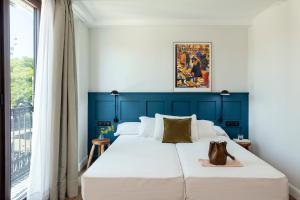 Dormitorio azul y blanco con cama y ventana en Som Nit Port Vell, en Barcelona