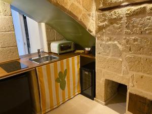 a kitchen with a sink and a stone wall at Casa Vacanze Disque Rouge in Trani