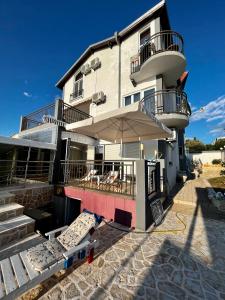 a building with a balcony and an umbrella at Villa Bojana in Utjeha