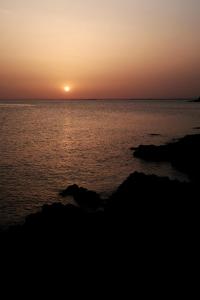 a sunset over the ocean with rocks in the foreground at House Mateja Unije in Unije