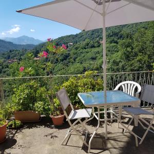 una mesa con sillas y una sombrilla en el balcón en Appartamento nel Verde, en Mosso Santa Maria