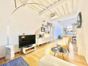 a living room with white walls and a flat screen tv at La Casa Del Pesce - Within the Historical Walls of Lucca in Lucca