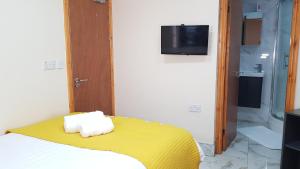 a bedroom with a bed with a yellow blanket and a television at Double Ensuite Rooms Near City Centre in Birmingham