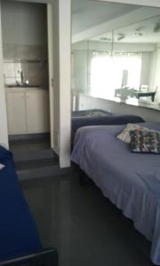 um quarto com duas camas e uma cozinha ao fundo em Dpto 2 pers x dia 17mil PESOS em Tres Arroyos