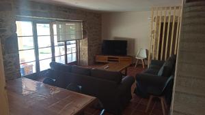 sala de estar con sofá, mesa y TV en Veiga da Porta - Casa Rural, en Ciquiril
