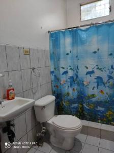 La salle de bains est pourvue de toilettes et d'un rideau de douche avec des poissons. dans l'établissement Casa y Hospedaje Norma, à Moyogalpa