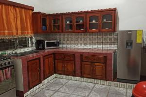 - une cuisine avec des placards en bois et un four micro-ondes dans l'établissement Casa y Hospedaje Norma, à Moyogalpa