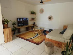 a living room with a bed and a tv at Ti Kaz À Patou, au coeur de l'île. in Baie-Mahault