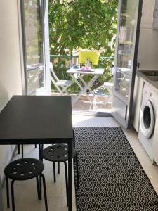 a black table and chairs in a kitchen with a balcony at Appartement de charme Avignon CENTRE HISTORIQUE TERRASSE et BALCON Place PIE in Avignon