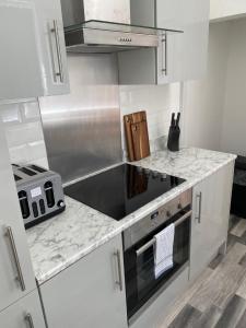 a kitchen with white cabinets and a stove top oven at Mitchell Heights in Pontnewynydd