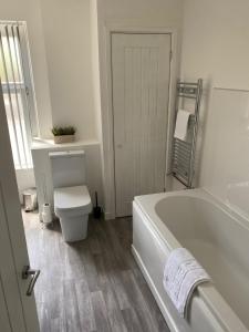 a white bathroom with a tub and a toilet at Mitchell Heights in Pontnewynydd