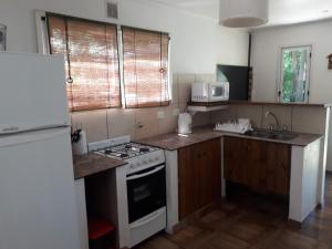 a kitchen with a stove and a sink and a refrigerator at Complejo de Cabañas Villapaz in Mar del Plata