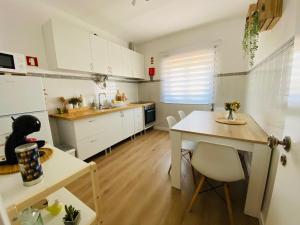 a kitchen with white cabinets and a table and chairs at Casa Margarida in Apúlia