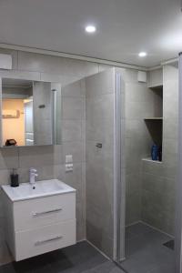a bathroom with a shower and a white sink at Romslig og fin leilighet 17 min til Kristiansand Centrum in Nodeland +9 photos