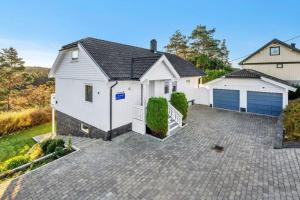 a white house with a garage on a driveway at Romslig og fin leilighet 17 min til Kristiansand Centrum in Nodeland