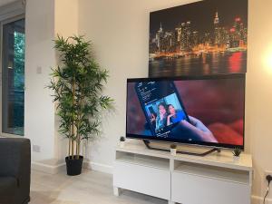 a flat screen tv sitting on a white stand in a living room at Luxe Haven King Bed En-suite & Double with Parking in London