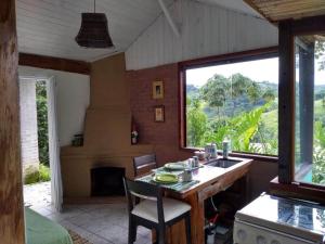 a kitchen with a table and a large window at Sítio Monte Moriá Pousada in Santo Antônio do Pinhal