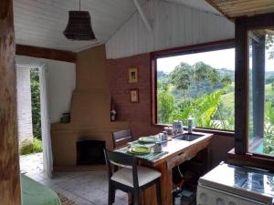 cocina con mesa y ventana grande en Sítio Monte Moriá Pousada en Santo Antônio do Pinhal