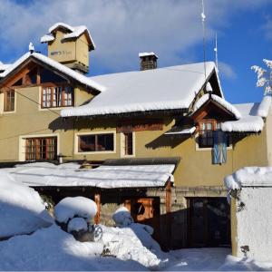 una casa coperta da neve con tetto ricoperto di neve di Periko´s Youth Hostel a San Carlos de Bariloche