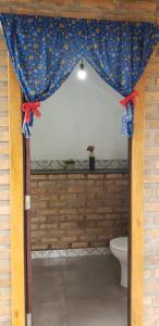 a bathroom with a toilet and a curtain at Chalés e Suítes Campos de São João in Palmeiras