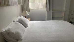 a white bed with white pillows and a window at Kiwi Heritage Homestay in Auckland
